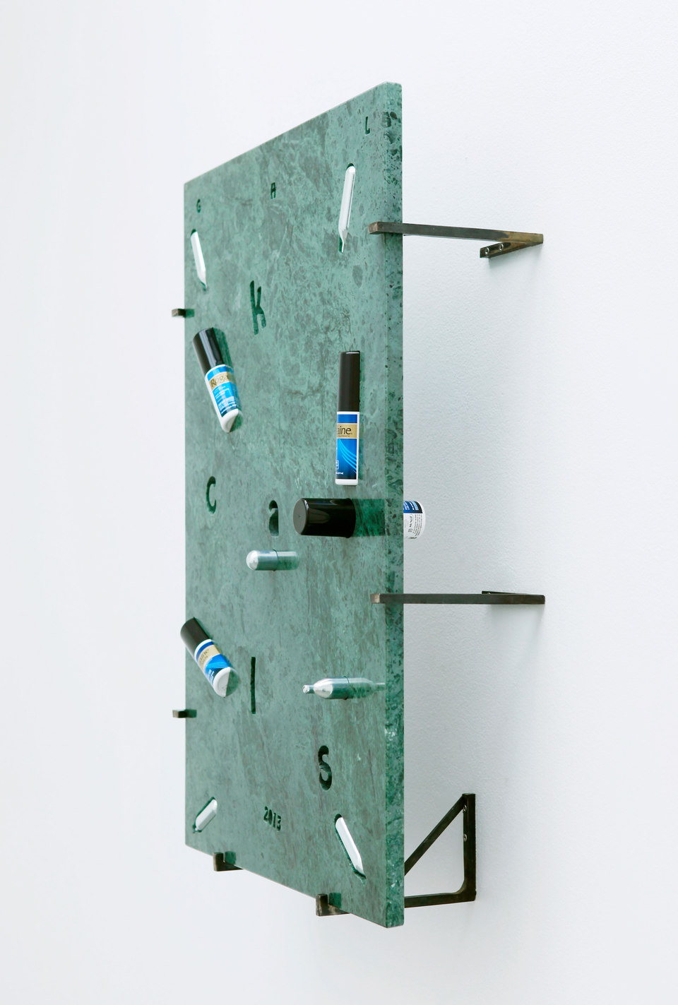 George Henry Longly, 2013: Year of the Snake, 2013, Verde Guatamala marble, whipping cream, chargers (nitrous oxide / laughing gas), Regaine (UK), Rogaine (US), Manifique (gay magazine), steel stand off fixings, 57 x 82 x 18 cm, Cell Project Space