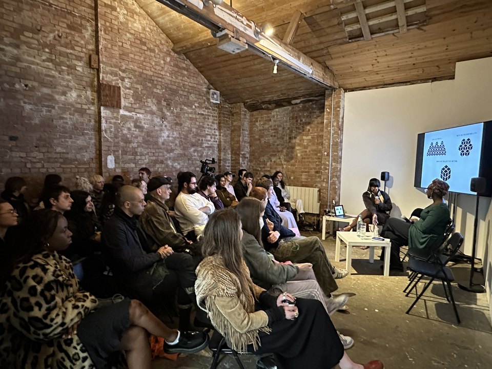 An image showing the panellists in front of a big screen facing the audience.